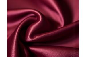 Tekstur kain sutra berkilau dalam warna maroon, elegan dan halus.